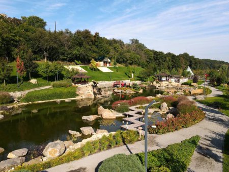 See im Landschaftspark im japanischen Stil. Schöne Landschaft, See, hölzerne Pavillons, rote Brücke. Luftaufnahme des Parks von der Drohne aus. Uman, Ukraine,