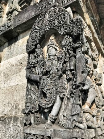 Vamana (Vishnu's avtar) statue on ornate wall panel at Chennakesava temple complex, Belur, Karnataka, India. Right slide low angle.