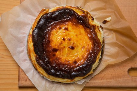 Freshly baked Basque cheesecake lies on parchment paper, on a board, flat lay