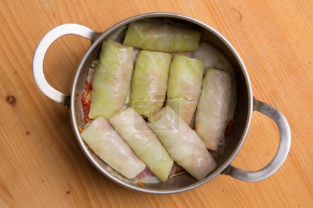 Saucepan with cabbage rolls on a wooden board, home cooking, flat lay