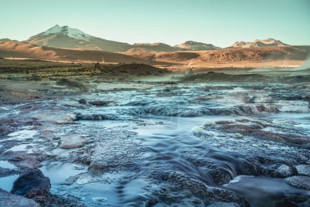 Geysers El Tatio with river and Peaceful dramatic volcanic landscape at sunrise, Atacama Desert, Chile