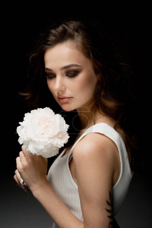 Téléchargez les photos : Portrait de jeune femme à la mode posant en studio avec des fleurs - en image libre de droit