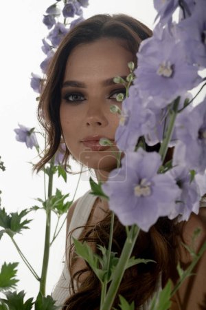 Téléchargez les photos : Portrait de jeune femme à la mode posant en studio avec des fleurs - en image libre de droit