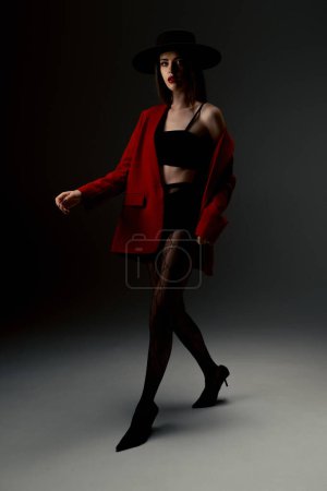 Foto de Young girl in a hat and a red jacket poses in the studio - Imagen libre de derechos