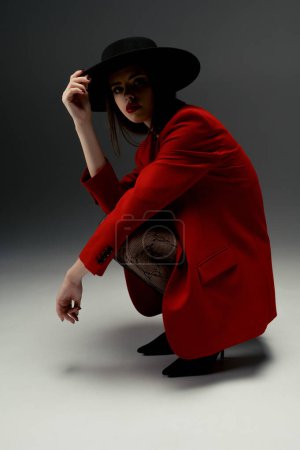 Téléchargez les photos : Young girl in a hat and a red jacket poses in the studio - en image libre de droit