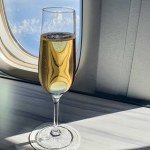 glass of champagne in flute on table in aircraft cabin near airplane window. Luxury travel concept, flying business class