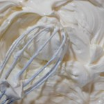 close up of a bowl of cream with whisk, texture of mascarpone soft cream cheese, cooking process 