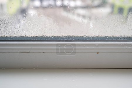 Téléchargez les photos : Fuites ou condensation dans le rebord de la fenêtre, gouttes de pluie sur la fenêtre, fuite d'eau à l'intérieur, humidité élevée dans la maison, la pièce nécessite une réparation - en image libre de droit