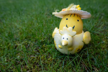 gelb gefärbte Osterei Lächeln Hut in der Hühnerform Keramikhalter auf grünem Hintergrund. Frohe Ostern. Er steht auf 