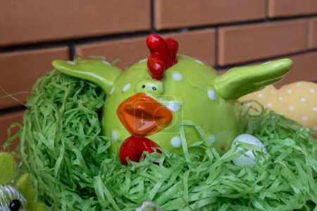 Photo for Easter chicken ceramic figure on green grass in nest with eggs. Happy Easter holiday - Royalty Free Image