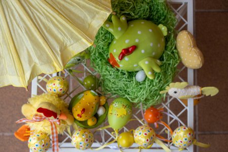 Feliz decoración de Pascua. Composición hecha de coloridos huevos de Pascua teñidos cerca de la figura de pollo de cerámica en una cesta de nido de paja