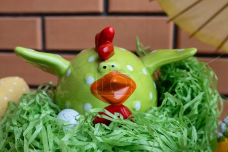 Photo for Easter chicken ceramic figure on green grass in nest with eggs. Happy Easter holiday - Royalty Free Image