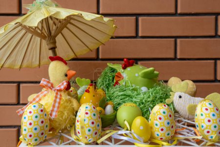 Happy easter decoration. Composition made of colorful dyed easter eggs near ceramic chicken figure in a straw nest basket
