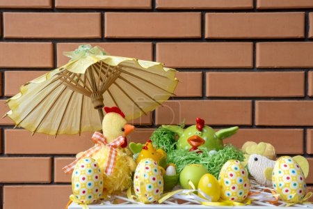Feliz decoración de Pascua. Composición hecha de coloridos huevos de Pascua teñidos cerca de la figura de pollo de cerámica en una cesta de nido de paja