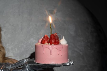 glamoroso pastel de cumpleaños de fresa rosa especialmente para mujer con vela encendida. Pide un deseo, sopla una vela. Efecto de la luz de las estrellas sobre la llama brillante, estrella ardiente. Día de celebración