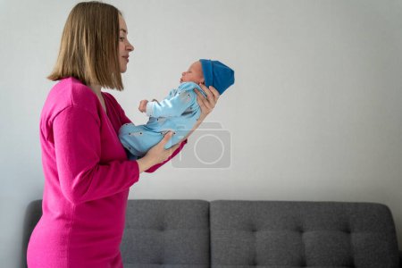Eine junge liebevolle Mutter hält ihren neugeborenen Sohn in den Händen. Säugling betreuen, Eltern sein, Kinder zu Hause großziehen