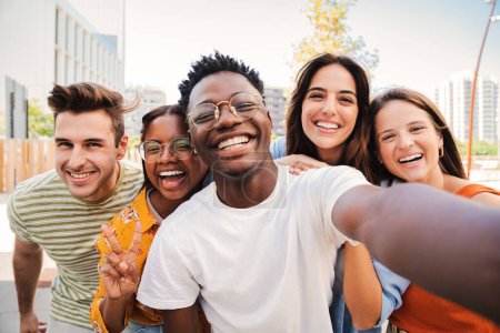 Grupo de jóvenes estudiantes multirraciales sonriendo y tomando una selfie juntos. Retrato de cerca de un adolescente afroamericano feliz riéndose con sus amigos alegres. Compañeros de clase en reunión amistosa