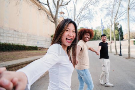Photo for Point view portrait of a multiracial group of friends walking holding hands. pov of young people having fun running hand in hand. First person perspective of three happy teenagers enjoying. friendship - Royalty Free Image