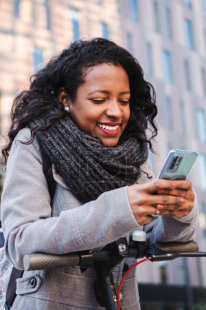 Photo for Vertical portrait of business young woman texting and browsing on smartphone at office workplace outside. Smiling cheerful girl having fun and laughing using a cellphone social media app. High quality - Royalty Free Image