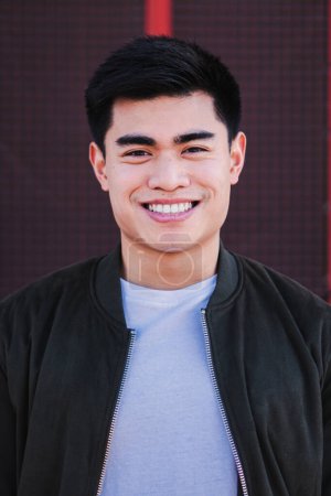 Photo for Vertical close up portrait of an asian young guy smiling looking at camera. Isolated teenage male with cheerful expression. Front view of real positive freelance man laughing with carefree attitude - Royalty Free Image