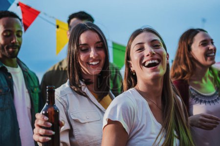 Photo for Two young women dancing and having fun with a happy group of best friends at music fest, enjoying and having fun at a party together. Playful people celebrating a weekend night event, social gathering - Royalty Free Image
