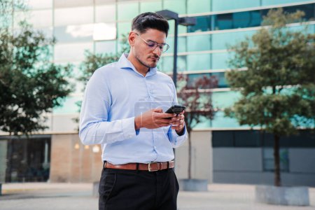Photo for Serious business man, salesman, manager or broker having a serious conversation using his mobile phone or reading text messages. Handsome and focussed businessperson browsing internet with a cellphone - Royalty Free Image