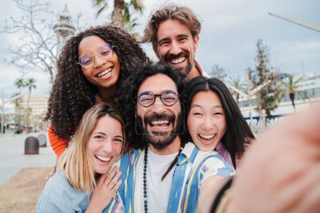 Téléchargez les photos : Groupe de jeunes adultes multiraciaux souriant prenant un selfie ensemble pour partager sur l'application de médias sociaux. Gros plan portrait de meilleurs amis heureux riant et s'amusant sur une réunion drôle. Haut - en image libre de droit