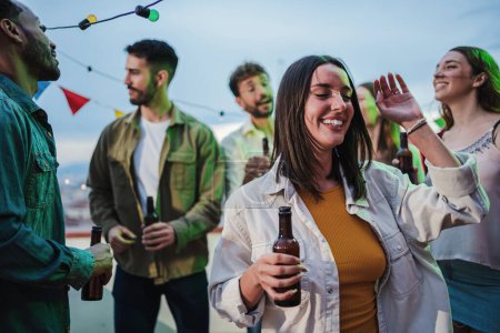 Photo for Close up portrait of excited young adult woman having fun dancing on a rooftop party with her friends. Carefree and joyful female enjoying the music at night fest celebration event with vitality. High - Royalty Free Image