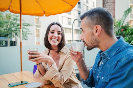Photo for Happy caucasian young couple taking a break after shopping on a coffee shop terrace, enjoying the moment together. Joyful woman with a toothy smile looking her boyfriend drinking coffe. High quality - Royalty Free Image