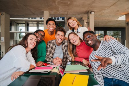 Photo for Happy young university students smiling and looking at camera enjoying together sitting in the library or classroom. Multiracial teenage friends laughing on a study break at campus. High school people - Royalty Free Image