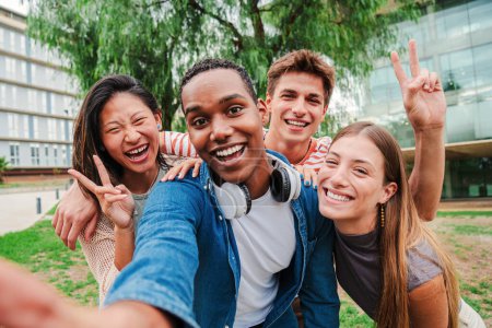 Téléchargez les photos : Groupe de jeunes étudiants multiraciaux souriant et prenant un selfie ensemble. Des camarades de classe en réunion amicale. Gros plan portrait de heureux adolescent afro-américain riant avec ses amis joyeux - en image libre de droit