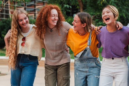 Photo for Group of joyful college student women in casual clothing, laughing and enjoying a nice weekend. Real cool girls walking embracing with toothy smile together. Happy female friends having fun outside - Royalty Free Image