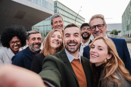 Téléchargez les photos : Grand groupe de gens d'affaires souriant en prenant un portrait selfie toguether. Une foule de gens d'affaires regardant la caméra. L'équipe de start-up s'amuse. Joyeux associé bien habillé. Haut - en image libre de droit