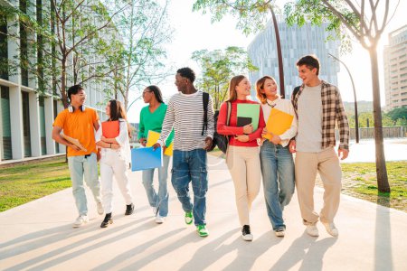 Photo for Big group of multiracial students walking together at university campus. Happy internacional teenagers laughing while going to class. Young friends back to school. Classmates on friendly meeting. High - Royalty Free Image