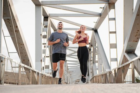 Téléchargez les photos : Jeune couple courir pour la santé, le bien-être ou l'entraînement pour un marathon, une compétition ou une course, montrant l'effort et l'endurance en appréciant le sport cardio. Entraînement d'un homme de fitness et de jogging femme athlétique - en image libre de droit
