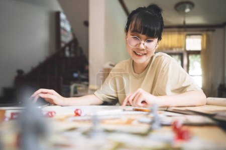 Photo for Role playing tabletop and board game hobby concept. Young adult asian woman enjoying with storytelling. Blur foreground with monster miniatures and dice component. - Royalty Free Image