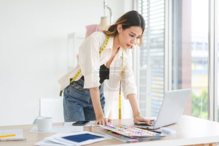 Foto de People working in fashion design concept. Young adult asian woman designer using laptop computer for online social media marketing. - Imagen libre de derechos