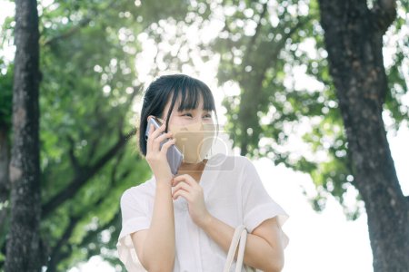 Téléchargez les photos : Young adult business asian working woman wear face mask for protect virus corona or covid19 and air pollution. Using mobile phone for talk. Urban people lifestyle with public health on day concept. - en image libre de droit