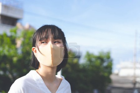 Téléchargez les photos : Young adult asian woman wear face mask for protect virus covid19. City people new normal lifestyle with public health on at outdoor on with sunlight day concept. - en image libre de droit