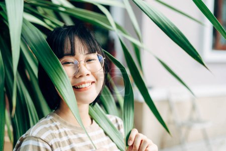 Photo for Young adult asian woman satisfaction lifestyle at home. People hobby gardening in green environment backyard at outdoor day. Wellness happy face wear eyeglasses. - Royalty Free Image