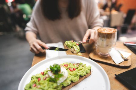 Photo for Guacamole avocado healthy food top on bread toast. Asian woman background at outdoor restaurant on day. City people lifestyle on weekend concept. - Royalty Free Image