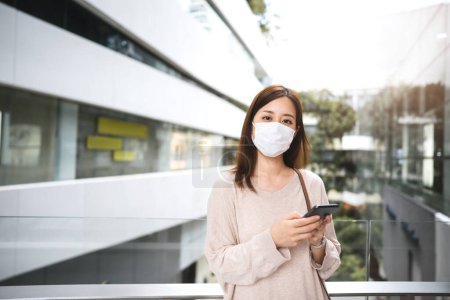 Photo for Portrait of business adult asian woman wear protective face mask for virus corona or covid19. Using mobile phone at shopping mall for message online dating. New normal urban lifestyle people concept. - Royalty Free Image