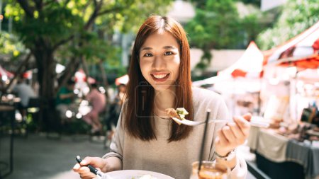 Foto de Young adult asian woman eat lunch wellness and healthy food. At mall park outdoor restaurant on day. Relax city lifestyle people on weekend. - Imagen libre de derechos