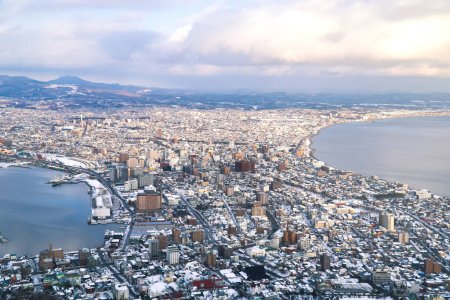 Téléchargez les photos : Hakodate bay cityscape dramatic scene  view from observation point up on mountain. Famous destination panorama of town and sea. Skylight before sunset. Hokkaido, Japan. - en image libre de droit