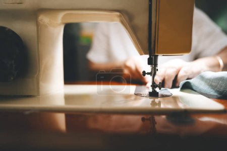 Photo for Closed up sewing machine and blur background with retriement tailor no face crafting a cloth. Baby boomer generation mature working at home concept. - Royalty Free Image