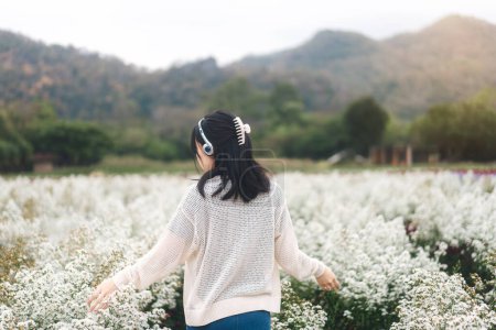 Téléchargez les photos : Voyage en plein air dans la nature concept. Haut de la montagne vue arrière jeune femme asiatique adulte portant casque dans le champ de parc de fleur de fleur sur le printemps. - en image libre de droit