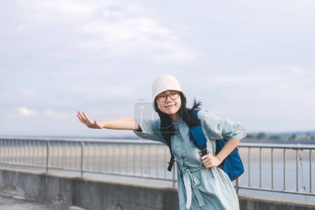 Foto de Joven adulto asiático viajero mujer con azul mochila. De pie en las gafas de desgaste al aire libre y sombrero. Llamar a los taxistas solo viajar en vacaciones de verano concepto - Imagen libre de derechos