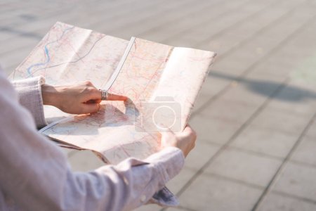 Téléchargez les photos : Femme asiatique point de main sur la carte pendant le voyage à l'extérieur le jour. Personnes célibataires solo touriste en vacances concept. - en image libre de droit