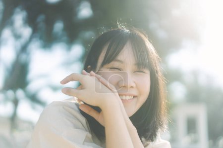 Foto de Retrato de sonrisa feliz mujer asiática con pelo corto. Minimal simplemente moda de estilo. Fondo al aire libre en el día con luz solar. - Imagen libre de derechos