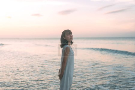 Foto de Retrato de mujer asiática en la playa. Caminando en las olas del mar Fondo de luz solar. Estilo de vida al aire libre en concepto de día. - Imagen libre de derechos